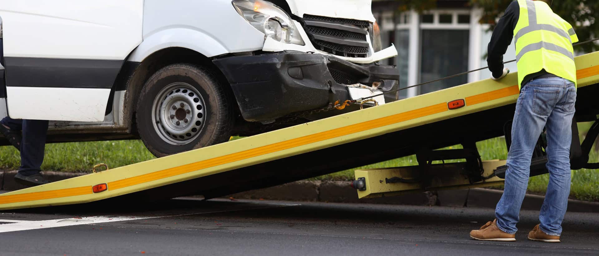 Crashed minibus is loaded onto tow truck after an accident. Evacuation and towing services concept